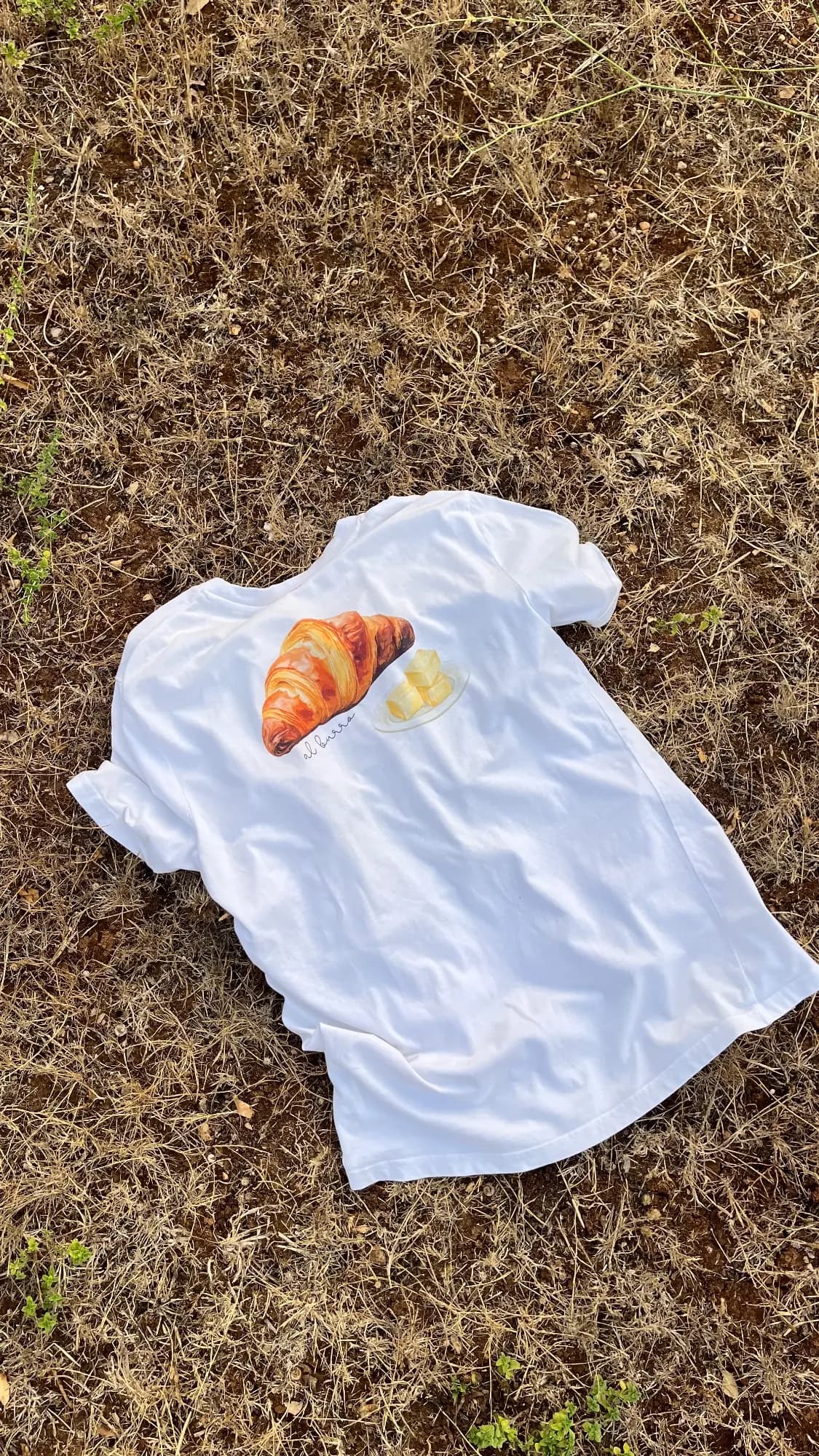 Michela Sharon regge due t-shirt Paneelatte di spalle tra gli alberi